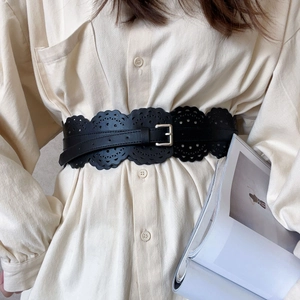 Gros plan d'une ceinture large noire ajourée avec boucle argentée sur une chemise