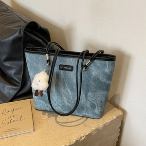 Chic blue denim tote bag with black leather handles and a plush cloud keychain