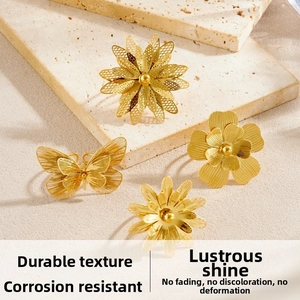 Detailed view of gold-plated hollow butterfly and textured floral rings on stone