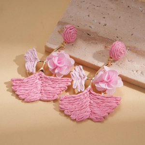 Detailed macro view of pink raffia flower earrings on a textured stone surface