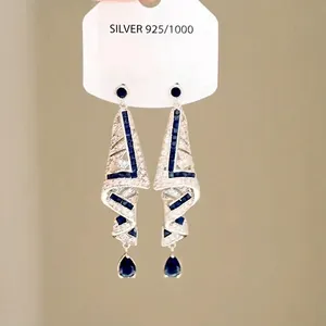 Detailed view of silver long geometric earrings with blue crystals and pear pendant