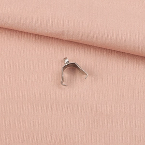 Macro shot of a silver stainless steel pinch bail clasp on soft pink fabric background