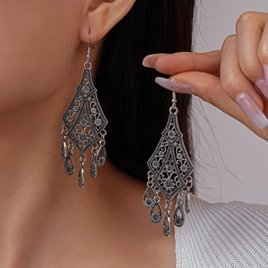 Bohemian vintage hollow flower drop earrings in antique silver finish worn by a model