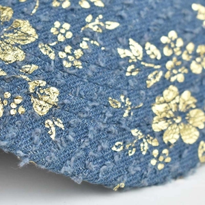Macro detail of brushed denim fabric with elegant gold floral foil printing on baseball cap