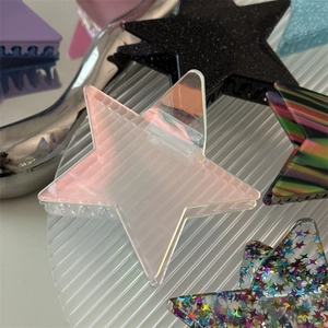 Detailed close-up of glittering star hair claws in various colors on textured glass