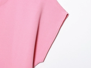 Close-up of pink knit fabric texture with soft ribbed details on a short sleeve top