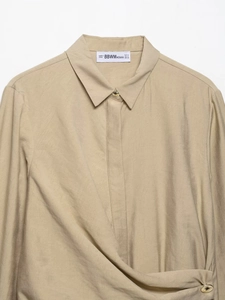 Detail of khaki blouse collar featuring gold button and BBWM woven size label