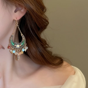 Bohemian crescent moon earrings with colorful sequins and fringe worn by a model