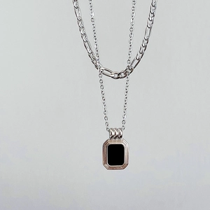 Detail view of double-layer silver chain featuring a vintage black rectangular pendant