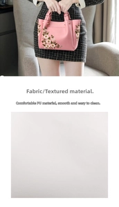 Close-up of pink PU leather handbag featuring floral embroidery and litchi grain texture