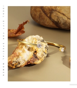 Detail of 18K gold-plated open bangle featuring double cubic zirconia on stone base