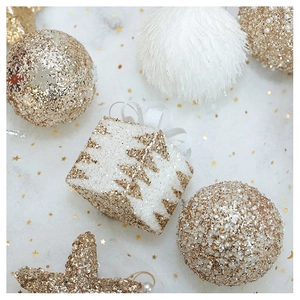Detailed flat lay of champagne gold Christmas ornaments with sequins and plush textures