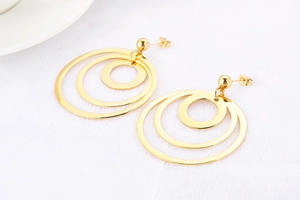 Detail of gold geometric earrings with three interlocking hollow circles on white texture