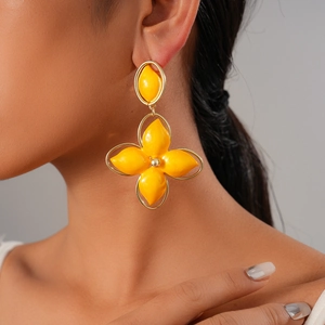Close-up of model wearing yellow oval flower drop earrings with golden metal borders