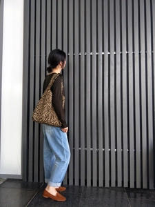 Dettaglio di una grande borsa tote in tela leopardata portata a spalla in stile casual