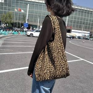 Vista dettagliata della grande borsa tote in tela leopardata indossata da una modella
