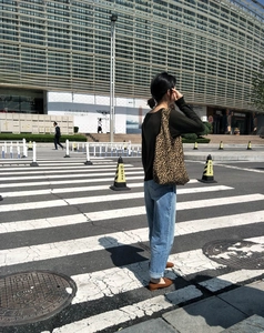Borsa tote in tela con stampa leopardata e spalline larghe mostrata in un ambiente esterno
