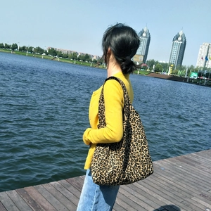 Scatto all'aperto di una borsa tote in tela con stampa leopardata portata a spalla da modella