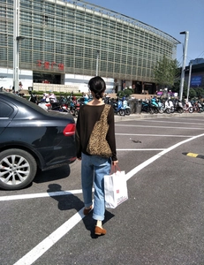 Grande borsa shopper in tela con stampa leopardata indossata da una modella all'aperto
