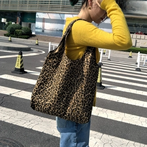 Scatto all'aperto di una borsa tote grande in tela leopardata con un look casual da strada