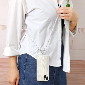 Detail showing white pearl crossbody phone strap with metal clasps on wavy white case