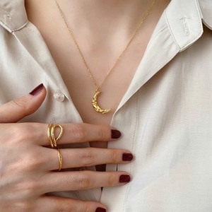 Close-up of minimalist gold plated moon pendant necklace and ring set on female model