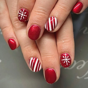 Nahaufnahme der Weihnachts-Nagelkunst mit rotem Glitzer und Schneeflocken-Mustern