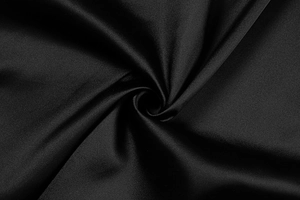 Macro shot of high-quality black satin fabric showing smooth texture and elegant drape