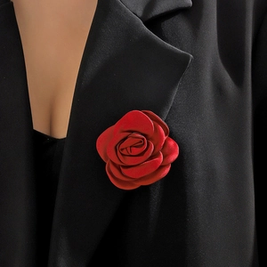 Close-up of a handmade red fabric rose brooch pinned on a black vintage style suit blazer
