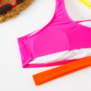 Dettaglio del top bikini bicolore con tessuto rosa, fascia arancione e cuciture fini