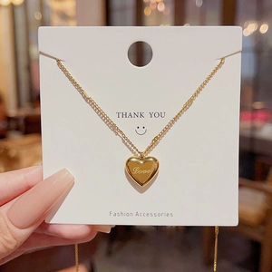 Detailed shot of gold heart necklace with Love engraving on a thank you card