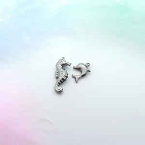 Detailed view of stainless steel seahorse and dolphin charms on decorative feathers