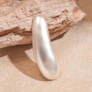 Macro detail of long teardrop brooch with champagne gold matte metallic texture