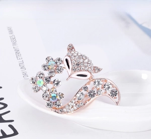 Détail d'une broche renard en or rose avec cristaux et strass colorés sur de la céramique