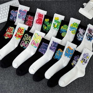 Athletic mid-calf socks with colorful graffiti text patterns on black and white knit fabric