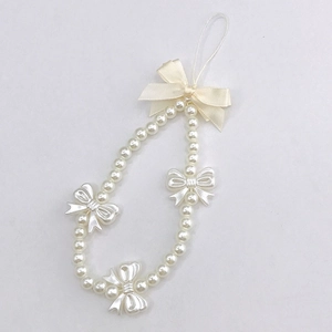 Close-up of pearl bead phone strap with plastic bows and cream ribbon detail