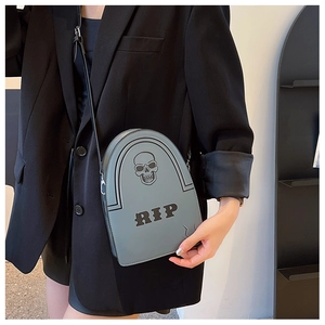 Détail du sac bandoulière gris en forme de tombe avec crâne et inscription RIP