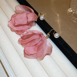 Detail of pink fabric flower earrings with faux pearl accent and golden metal clip-on back