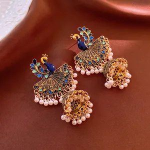 Vintage peacock tassel earrings with blue enamel and pearls on brown silk background