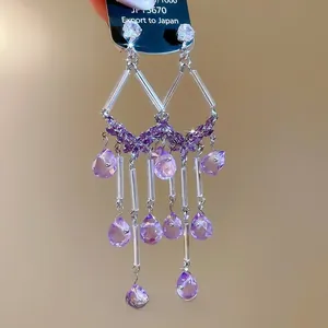 Macro shot of purple teardrop crystal fringe earrings with floral silver hardware details