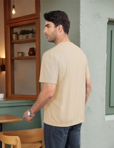 Detail of light beige textured knit fabric on a men's short sleeve crew neck casual shirt