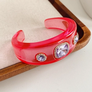 Detailed macro of vintage red resin cuff bracelet featuring inlaid purple gemstones and crystals