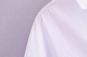 Vue macro de l'épaule d'une chemise blanche montrant le tissu lisse et les coutures