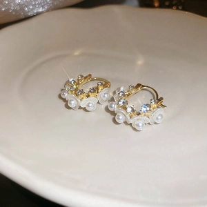 Close-up of golden hoop earrings featuring white pearl flowers and sparkling crystals