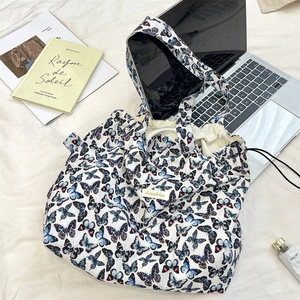 Detail of butterfly print tote bag with drawstring closure on white textured fabric