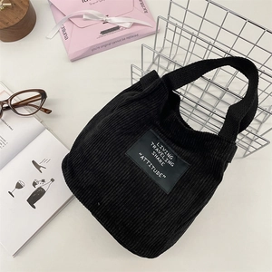 Gros plan détaillé du mini sac seau en velours côtelé noir avec étiquette minimaliste