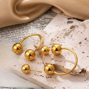 Close-up of golden spherical earrings with mirror finish on premium beige stone and silk