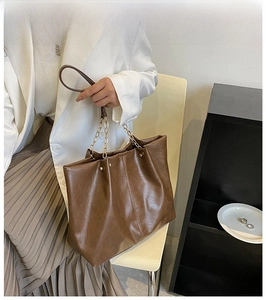 Détail d'un grand sac cabas marron en cuir PU avec chaîne dorée et rivets métalliques sur le côté