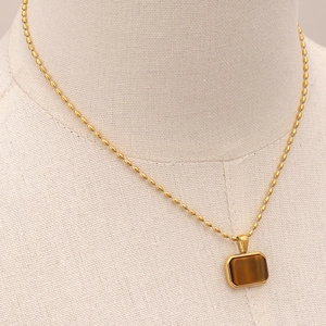 Detailed close-up of gold chain necklace with rectangular brown tiger eye stone pendant