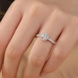 Détail macro d'une bague halo avec diamant rond et anneau pavé portée à la main